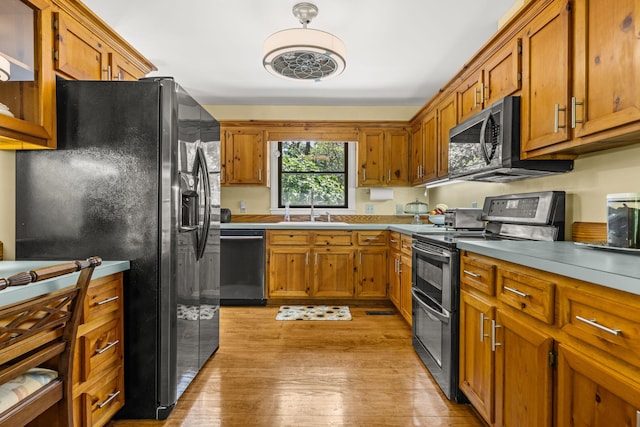 2144 Pinopolis Rd, Pinopolis, SC 29469 - kitchen with brown cabinetry, light wood-style floors, stainless steel appliances, and a sink