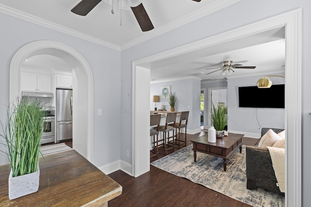 living room with arched walkways, dark wood-style flooring, baseboards, a ceiling fan, and crown molding