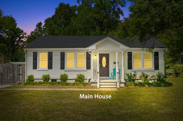 view of front of house featuring fence, roof with shingles, and a front yard