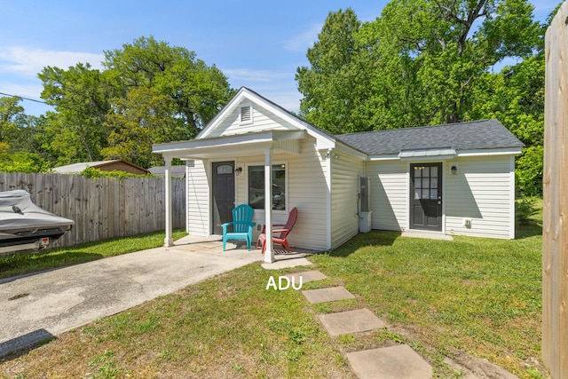 view of front facade featuring fence, a shingled roof, and a front yard