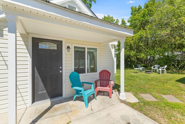 view of exterior entry with a porch and a yard