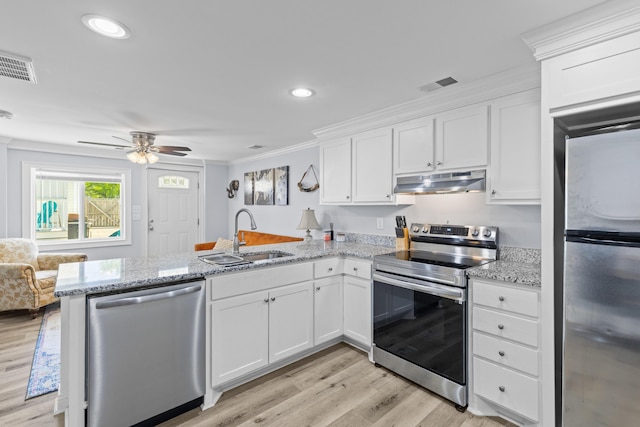 kitchen with a sink, stainless steel appliances, a peninsula, under cabinet range hood, and visible vents