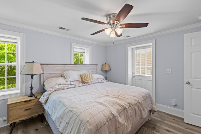 bedroom with wood finished floors, visible vents, baseboards, and ornamental molding