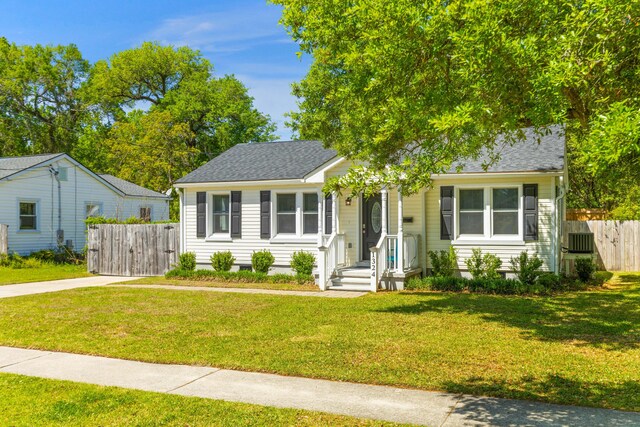 view of front of house featuring a front lawn, fence, and roof with shingles