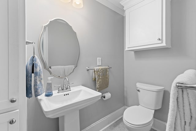 half bath featuring baseboards, toilet, and a sink