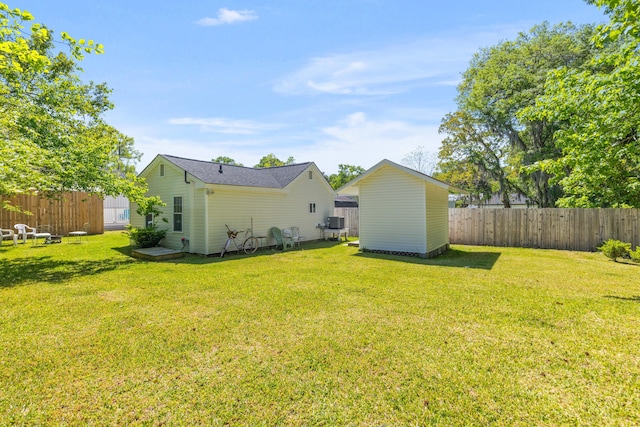 view of yard featuring an outdoor structure, a fenced backyard, and a storage shed