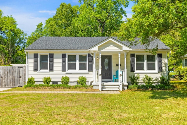 single story home featuring a shingled roof, a front yard, and fence
