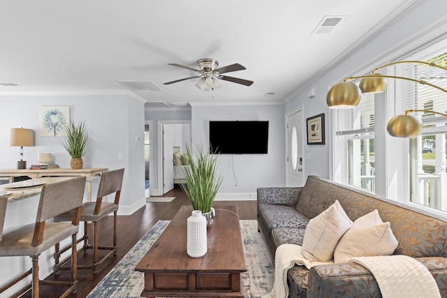 living room featuring visible vents, a ceiling fan, dark wood-type flooring, crown molding, and baseboards