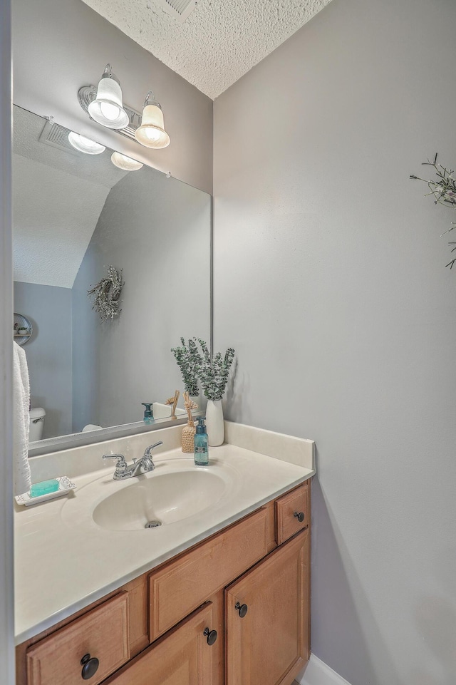 half bathroom featuring toilet, vanity, and vaulted ceiling