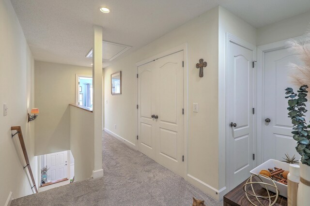 hall featuring baseboards, attic access, an upstairs landing, carpet flooring, and recessed lighting