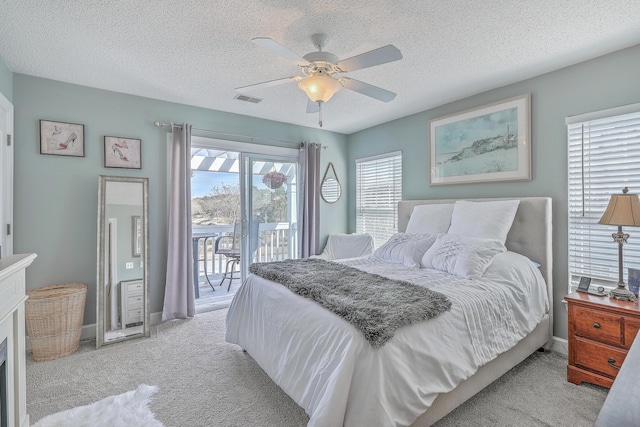 bedroom featuring a ceiling fan, visible vents, access to exterior, a textured ceiling, and light carpet