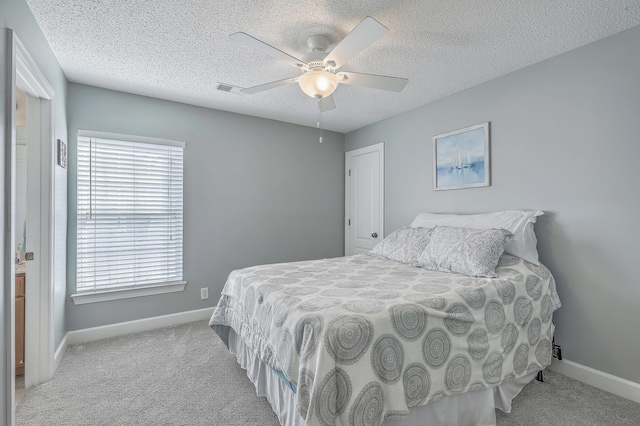 carpeted bedroom with visible vents, baseboards, a textured ceiling, and a ceiling fan