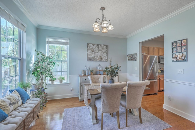 dining room featuring crown molding, baseboards, light wood-type flooring, a notable chandelier, and a textured ceiling