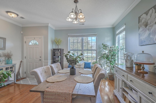 dining room with light wood-type flooring, visible vents, a chandelier, and crown molding