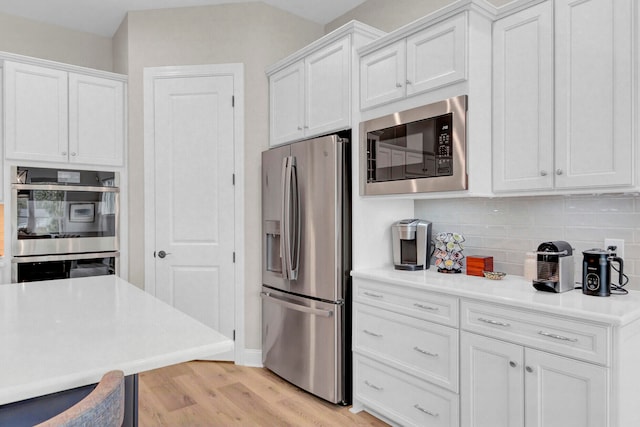 kitchen with white cabinets, stainless steel appliances, and light hardwood / wood-style flooring