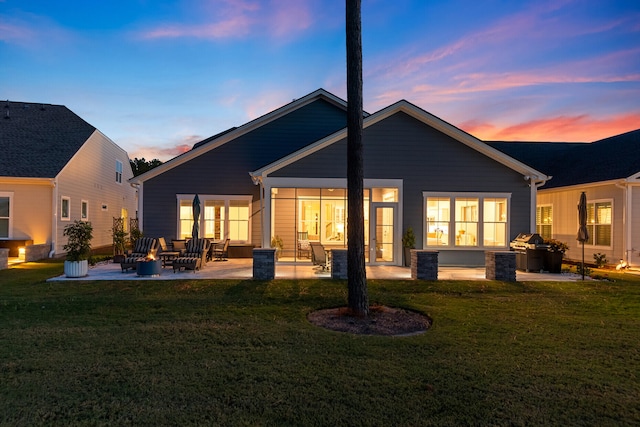 back house at dusk featuring a yard and a patio area