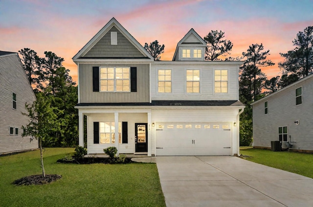 view of front of house with an attached garage, cooling unit, driveway, and a front lawn