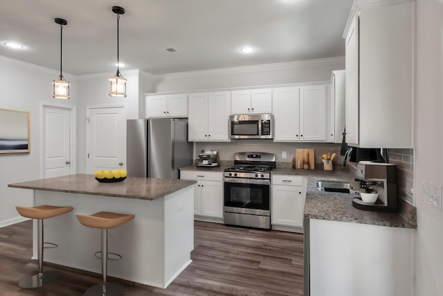 kitchen with ornamental molding, white cabinetry, appliances with stainless steel finishes, and backsplash