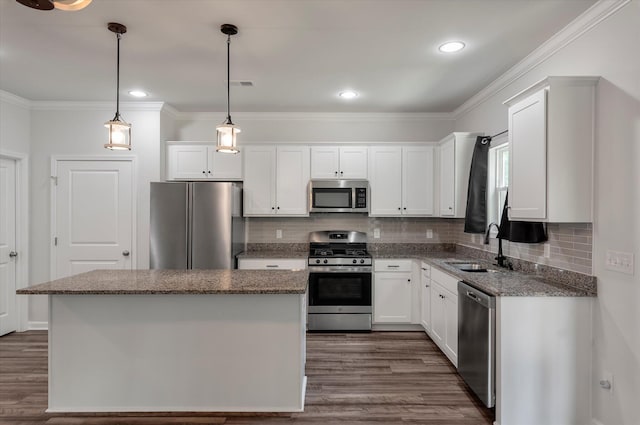 kitchen featuring decorative backsplash, a kitchen island, appliances with stainless steel finishes, a sink, and ornamental molding