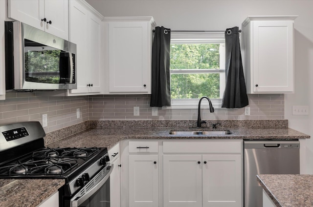 kitchen featuring appliances with stainless steel finishes, tasteful backsplash, a sink, stone countertops, and white cabinetry