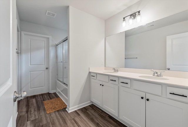 full bathroom with a sink, double vanity, wood finished floors, and visible vents
