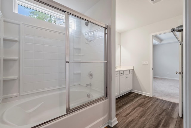 bathroom with shower / bath combination with glass door, baseboards, wood finished floors, and vanity