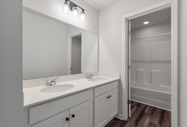full bathroom with double vanity, a sink, shower / tub combination, and wood finished floors