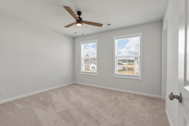 spare room featuring light colored carpet, baseboards, visible vents, and a ceiling fan
