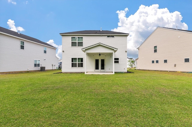 rear view of property featuring central air condition unit, a patio, ceiling fan, and a yard