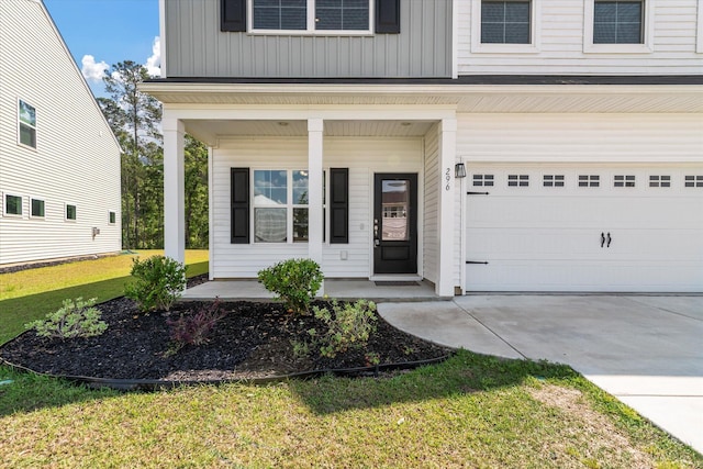doorway to property featuring a garage, covered porch, driveway, board and batten siding, and a yard