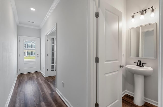 hallway featuring dark wood-type flooring, ornamental molding, baseboards, and visible vents