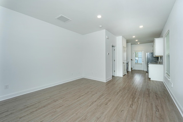 unfurnished living room featuring visible vents, recessed lighting, light wood-style floors, and baseboards