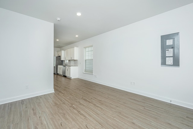 unfurnished living room with recessed lighting, baseboards, and light wood-type flooring