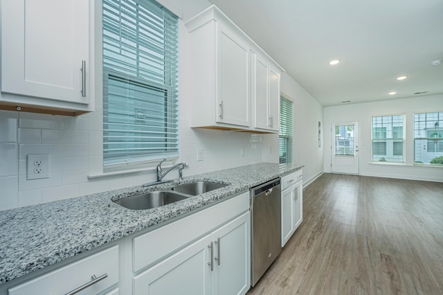 kitchen with light wood-type flooring, a sink, light stone counters, stainless steel dishwasher, and white cabinetry