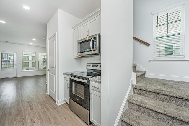 kitchen with light wood finished floors, recessed lighting, stainless steel appliances, decorative backsplash, and open floor plan