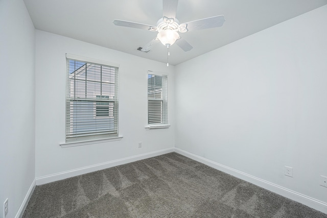 unfurnished room with a ceiling fan, visible vents, dark colored carpet, and baseboards