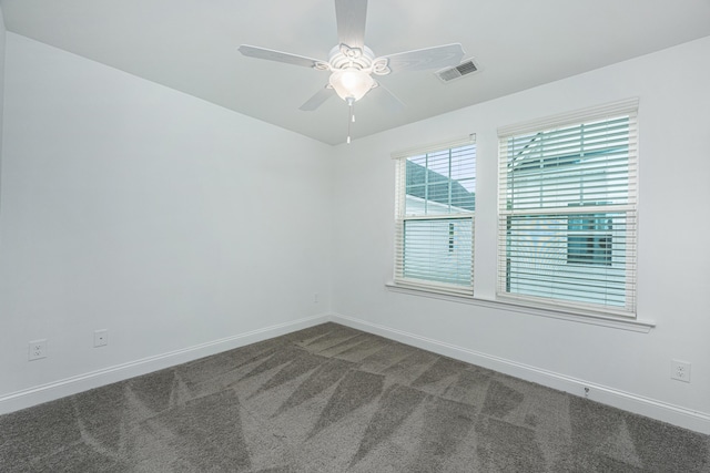 spare room featuring visible vents, baseboards, ceiling fan, and dark carpet