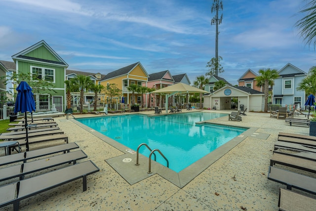 pool with a patio area, a residential view, and fence