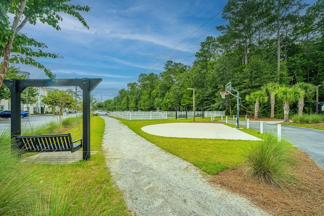 view of home's community with community basketball court, a yard, and fence