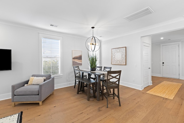 dining space with a chandelier, crown molding, and light hardwood / wood-style flooring