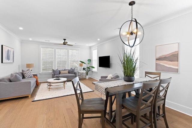 dining space with crown molding, light hardwood / wood-style floors, and ceiling fan with notable chandelier