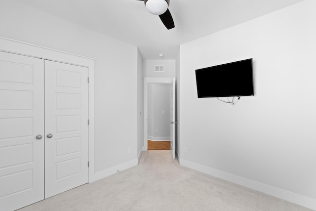 unfurnished bedroom featuring ceiling fan, a closet, and light colored carpet