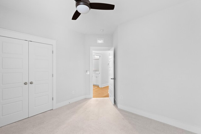 unfurnished bedroom featuring ceiling fan, light colored carpet, and a closet