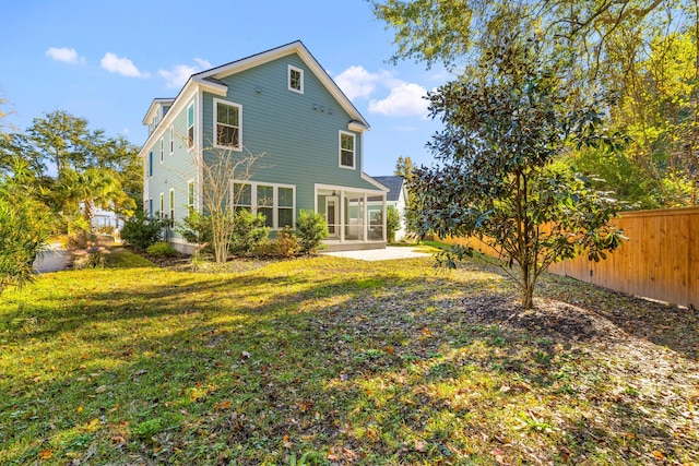 rear view of house with a lawn, a sunroom, and a patio area