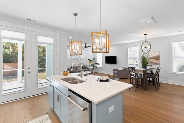 kitchen featuring pendant lighting, dishwasher, sink, an island with sink, and light hardwood / wood-style floors