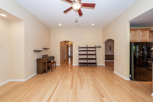 living area featuring arched walkways, a ceiling fan, light wood-type flooring, baseboards, and recessed lighting