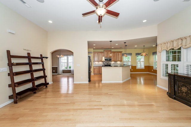 unfurnished living room featuring a ceiling fan, arched walkways, plenty of natural light, light wood-type flooring, and recessed lighting