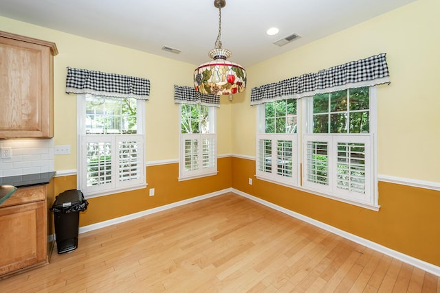 unfurnished dining area with light wood-style floors, plenty of natural light, and baseboards