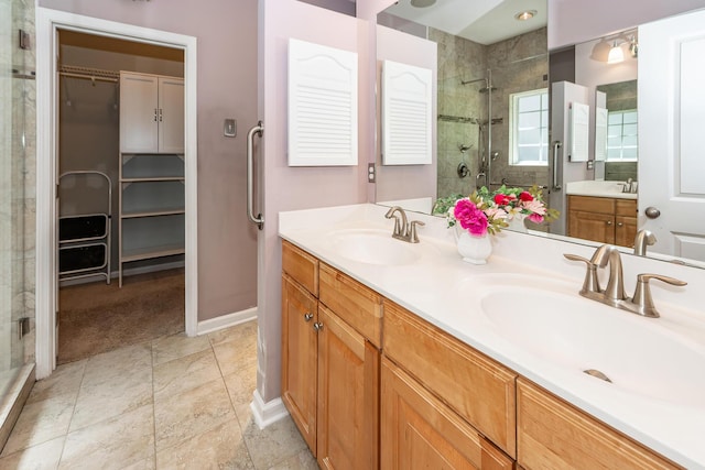 bathroom with a stall shower, a spacious closet, double vanity, and baseboards