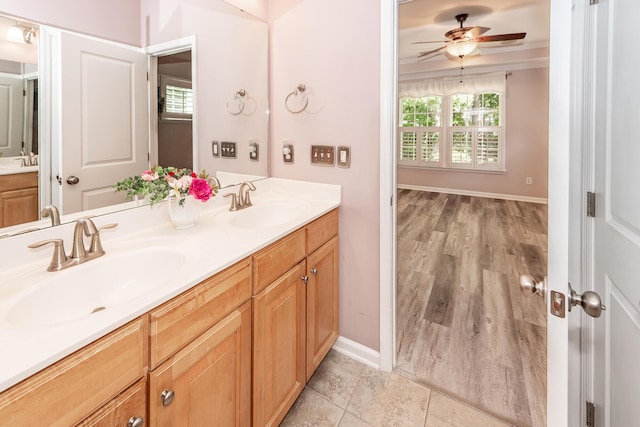 full bath with double vanity, a ceiling fan, baseboards, and ornamental molding